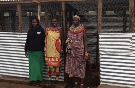 Members of a BOMA savings group standing next to the poultry farm they conducted for their new business